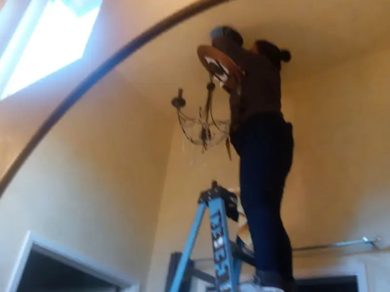 Electrician installing a chandelier in a Avon residence